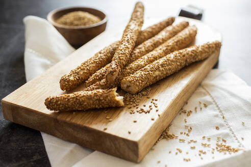 Cutting board and fresh Italian grissini breadsticks with sesame seeds - GIOF08226