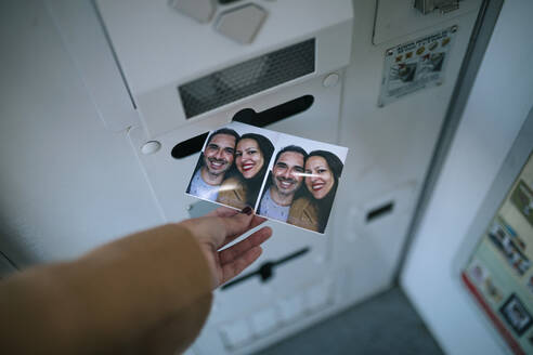 Frauenhand, die ein Foto aus einem Fotoautomaten entfernt - GRCF00257