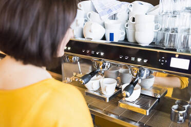 Female barista using espresso maker in coffee shop - DIGF12451