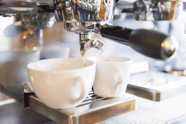 Nahaufnahme von Kaffee, der aus einer Espressomaschine im Geschäft in eine Tasse gegossen wird - DIGF12452
