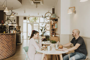 Smiling man and woman sitting at table in a coffee shop - GMLF00224