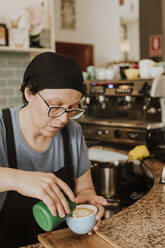 Portrait of waitress preparing Cappuccino in a coffee shop - GMLF00226