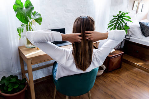 Mid adult woman sitting with hands in hair at home stock photo