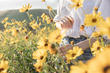 Frau hält Blume in gelbem Blumenfeld in der Werbung - CAVF83246