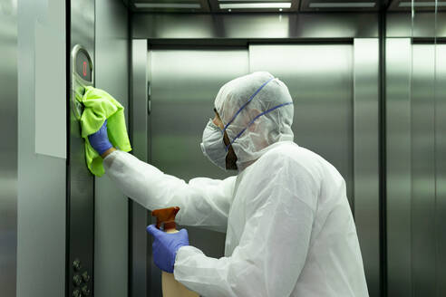 Coronavirus. Worker disinfecting hospital elevator to avoid contagion. - CAVF83284