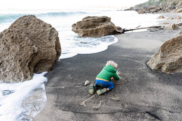 Kleines Kind schreibt in Sand am Strand in Neuseeland - CAVF83307