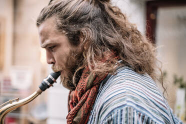 Saxophonist mit langen Haaren und Bart spielt auf der Straße - CAVF83372