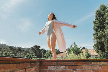 Frau trägt Badeanzug und genießt das Sonnenlicht auf dem Dach - AFVF06386