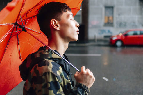 Man with umbrella on street during rainy season - MEUF00621