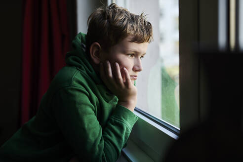 Bored boy looking out through window at home - MMIF00277