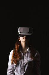 Junge Frau mit VR-Brille vor schwarzem Hintergrund - LJF01529