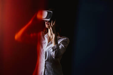 Junge Frau mit VR-Brille vor schwarzem Hintergrund - LJF01538