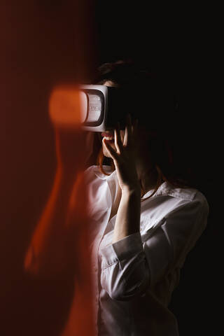 Junge Frau mit VR-Brille vor schwarzem Hintergrund, lizenzfreies Stockfoto
