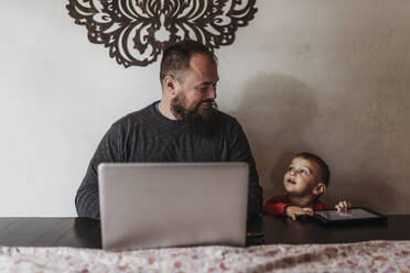 Work at home father working with young toddler during isolation - CAVF83474