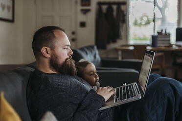 Close up of Dad working from home with young daughter - CAVF83485