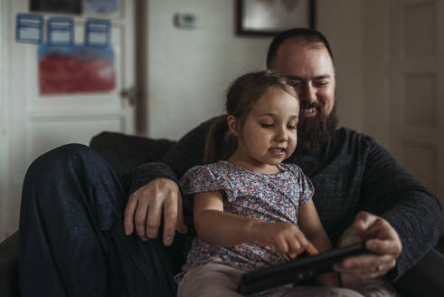 Nahaufnahme eines Vaters und einer kleinen Tochter, die während der Isolation auf einem Tablet spielen - CAVF83486