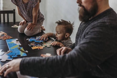 Family completing puzzle at home during isolation - CAVF83487