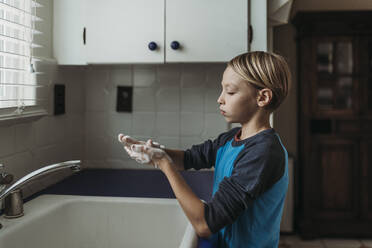 Seitenansicht eines Jungen im Schulalter beim Händewaschen am heimischen Waschbecken - CAVF83502