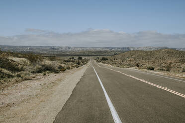 Lonely road with US Mexico border wall in distance near Jacumba, CA - CAVF83602