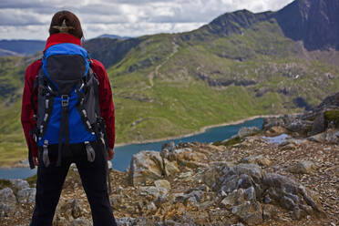 Frau mit Rucksack mit Blick auf einen Bergsee in Snowdonia - CAVF83630