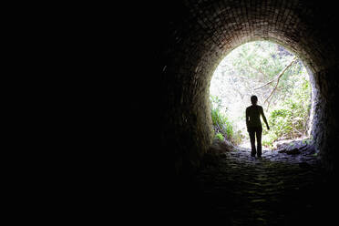 Woman standing in a tunnel opening - CAVF83633