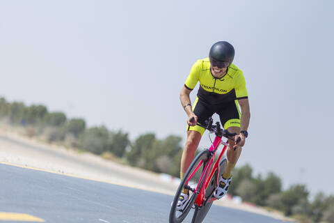 Entschlossener Radfahrer auf der Straße gegen den klaren Himmel, Dubai, Vereinigte Arabische Emirate, lizenzfreies Stockfoto