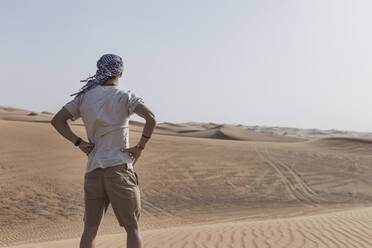 Junger männlicher Tourist steht auf Sanddünen in der Wüste von Dubai, Vereinigte Arabische Emirate - SNF00241