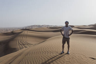 Glücklicher männlicher Tourist, der auf Sanddünen in der Wüste von Dubai, Vereinigte Arabische Emirate, steht - SNF00250