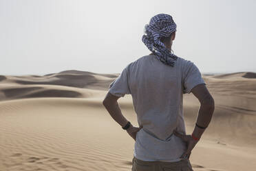 Männlicher Tourist steht auf Sanddünen in der Wüste von Dubai, Vereinigte Arabische Emirate - SNF00253