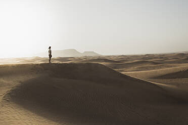 Mid distance of male tourist standing on sand dunes in desert at Dubai, United Arab Emirates - SNF00254