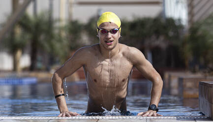 Selbstbewusster Schwimmer beim Aussteigen aus dem Pool in einer Ferienanlage, Dubai, Vereinigte Arabische Emirate - SNF00262