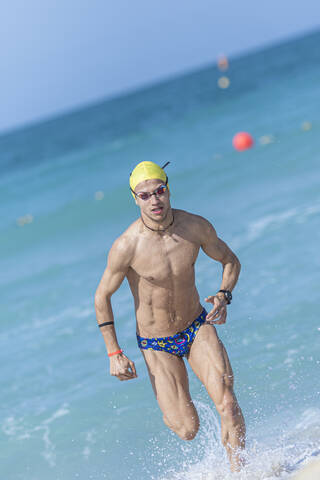 Männlicher Schwimmer beim Laufen am Strand in Dubai, Vereinigte Arabische Emirate, lizenzfreies Stockfoto