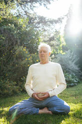 Senior man meditating in garden - AFVF06391