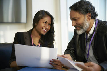 Smiling business people discussing paperwork in meeting - CAIF27536