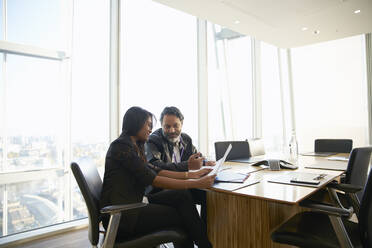 Business people discussing paperwork in conference room meeting - CAIF27541