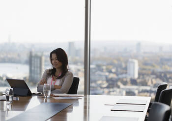 Businesswoman using digital tablet in highrise conference room - CAIF27619