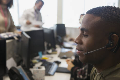 Geschäftsmann mit Headset bei der Arbeit im Büro - CAIF27624