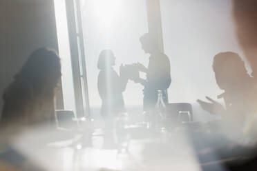 Silhouette Geschäftsleute im Gespräch in sonnigen Konferenzraum Fenster - CAIF27629