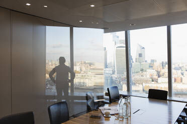 Silhouette Geschäftsmann stehend an städtischen Hochhaus Büro Fenster - CAIF27635