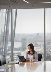 Businesswoman using digital tablet in urban highrise conference room - CAIF27657