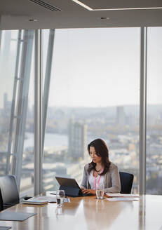 Geschäftsfrau mit digitalem Tablet im Konferenzraum eines städtischen Hochhauses - CAIF27657