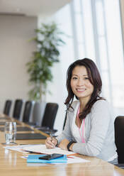 Porträt einer selbstbewussten Geschäftsfrau, die an einem Konferenztisch arbeitet - CAIF27661