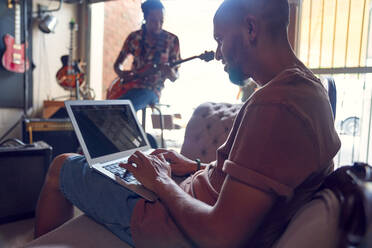 Musiker mit Laptop und Gitarre im Aufnahmestudio - CAIF27675