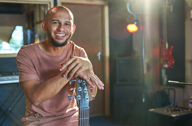 Porträt glücklicher, selbstbewusster männlicher Musiker mit Gitarre im Aufnahmestudio - CAIF27705
