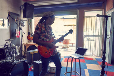 Männlicher Musiker spielt E-Gitarre in einem Aufnahmestudio in einer Garage - CAIF27718