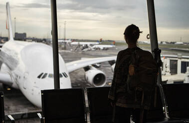 Südafrika, Johannesburg, Rückansicht einer Frau, die vom Flughafenterminal aus die Flugzeuge auf dem Rollfeld betrachtet - VEGF02340