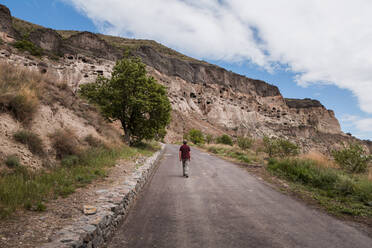 Georgien, Samtskhe-Javakheti, Männlicher Tourist auf der leeren Straße, die zum Höhlenkloster Vardzia führt - WVF01660