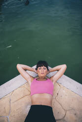 Woman doing sit-ups by pond at park - OCMF01314