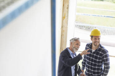 Architekt und Arbeiter im Gespräch auf einer Baustelle - MJFKF00204