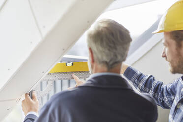 Architekt und Arbeiter messen Fenster auf einer Baustelle aus - MJFKF00205